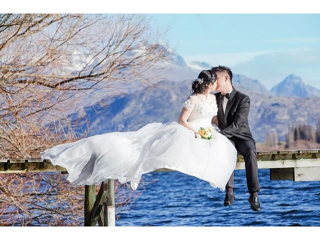 Newlyweds kissing on a deck above the water